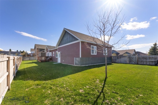 view of home's exterior featuring a lawn, a deck, and a fenced backyard