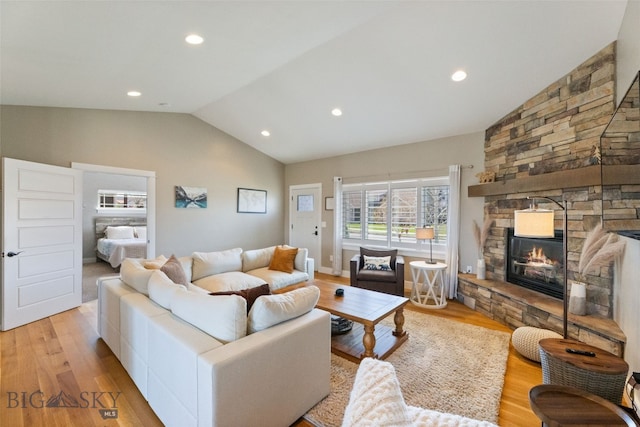 living room featuring light wood-style flooring, vaulted ceiling, recessed lighting, and a stone fireplace