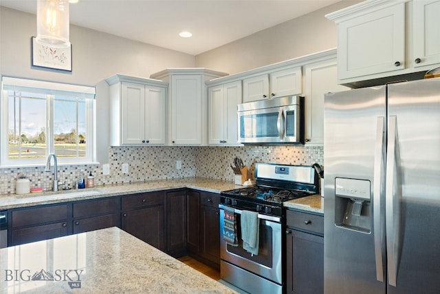 kitchen featuring a sink, white cabinetry, light stone countertops, and stainless steel appliances