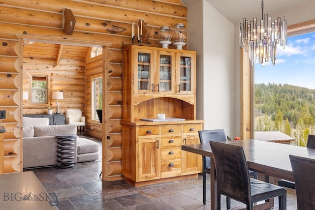 dining space with an inviting chandelier, stone tile floors, and rustic walls