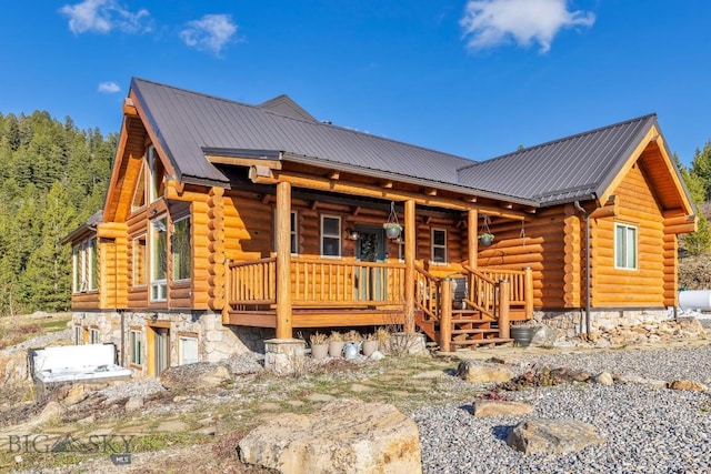 rear view of property featuring log siding, metal roof, and covered porch