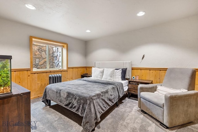 carpeted bedroom with recessed lighting, wood walls, wainscoting, and radiator