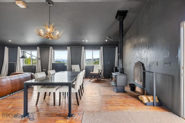 dining area featuring a chandelier, a wood stove, and hardwood / wood-style floors