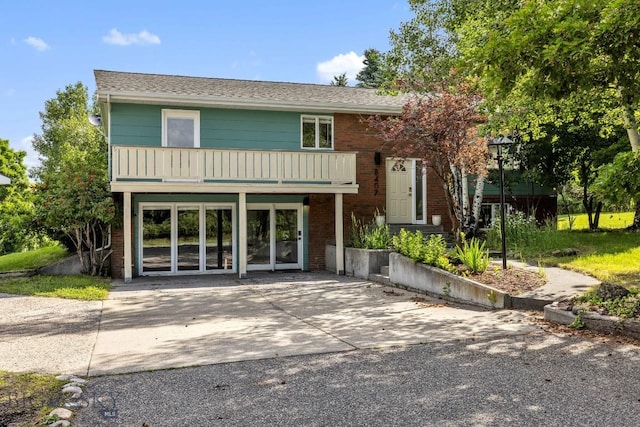 view of front of house with concrete driveway, brick siding, and a balcony