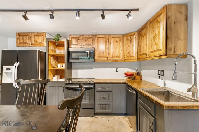 kitchen with stainless steel appliances, open shelves, track lighting, and a sink