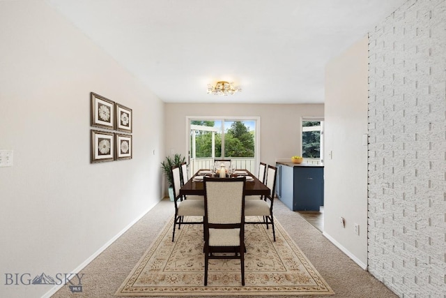 dining space with baseboards and light carpet
