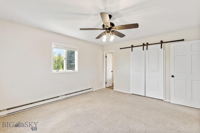 unfurnished bedroom with carpet floors, baseboards, a barn door, and baseboard heating