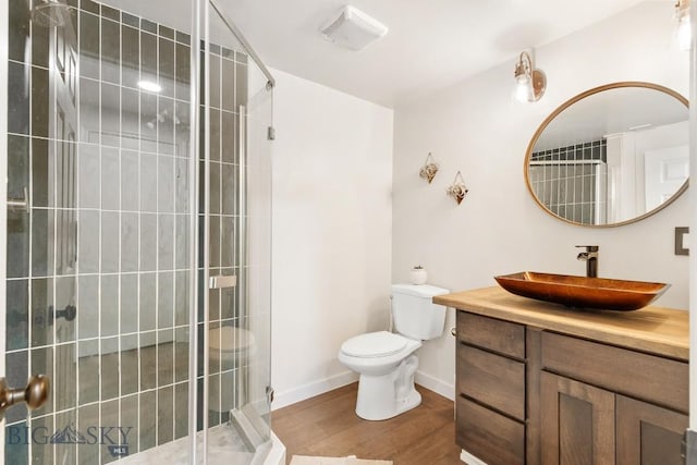 full bath with vanity, toilet, baseboards, wood finished floors, and a stall shower