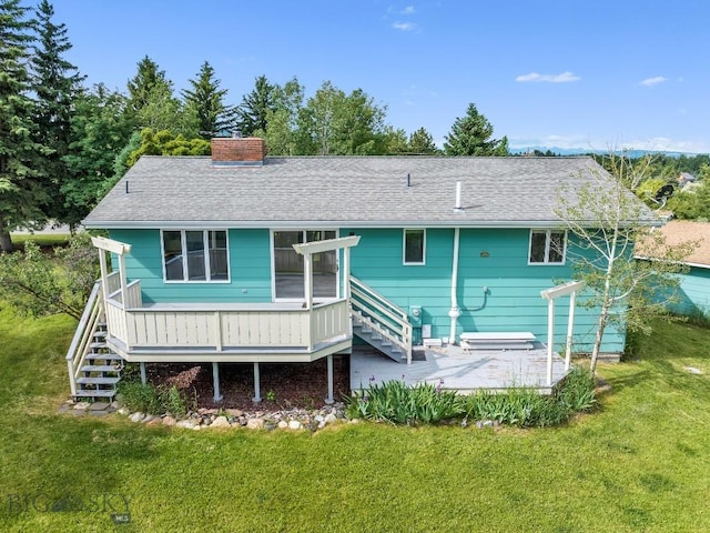 rear view of property featuring stairway, a yard, and a chimney