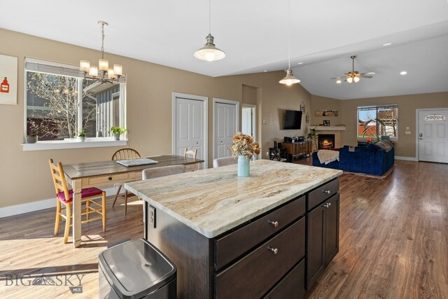 1604 Drummond Blvd, Belgrade, MT 59714 - kitchen featuring baseboards, ceiling fan with notable chandelier, a warm lit fireplace, and dark wood-style floors
