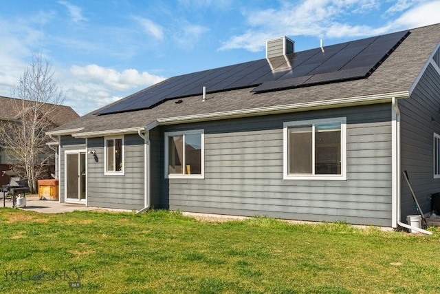 1604 Drummond Blvd, Belgrade, MT 59714 - back of property with a chimney, a shingled roof, roof mounted solar panels, a patio area, and a lawn