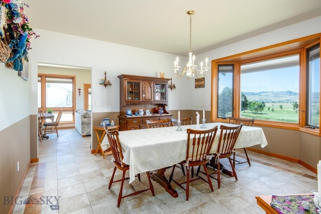 dining space with baseboards and a notable chandelier