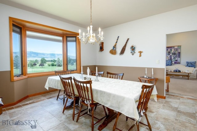 dining space with baseboards, a mountain view, and a chandelier