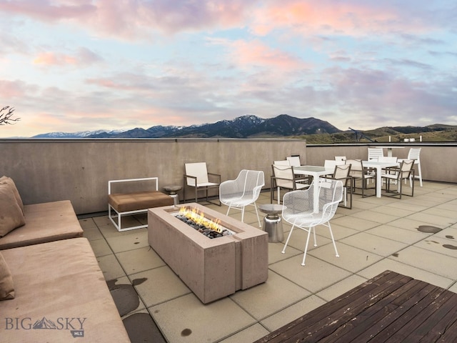 view of patio with outdoor dining area, an outdoor fire pit, and a mountain view