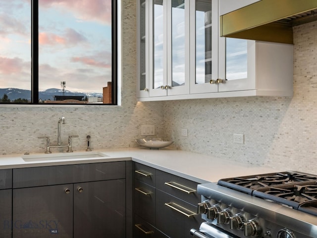 kitchen featuring light countertops, a sink, stainless steel gas range, and tasteful backsplash
