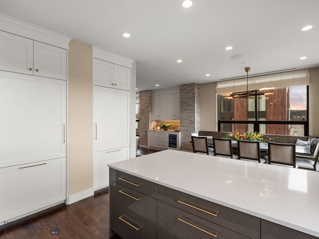 kitchen with dark wood-style flooring, an inviting chandelier, light countertops, white cabinetry, and recessed lighting