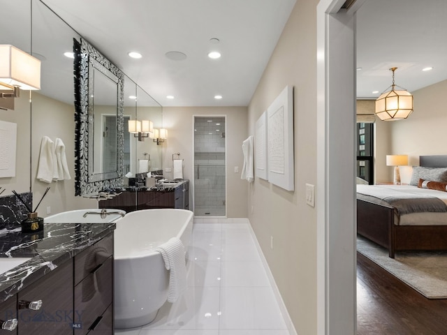 full bath with recessed lighting, a freestanding tub, baseboards, two vanities, and a stall shower
