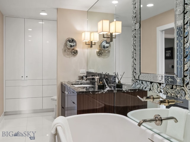bathroom featuring double vanity, a freestanding bath, a sink, tile patterned floors, and recessed lighting
