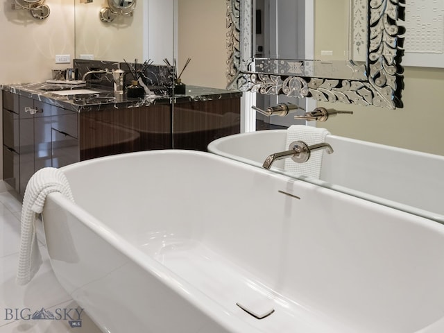full bath featuring a freestanding tub, tile patterned floors, and vanity