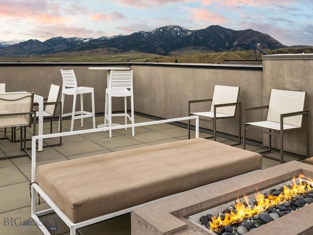 patio terrace at dusk featuring a fire pit and a mountain view