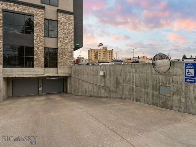 patio terrace at dusk featuring concrete driveway and an attached garage