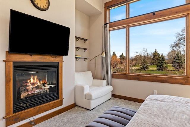 carpeted living room with a glass covered fireplace and baseboards