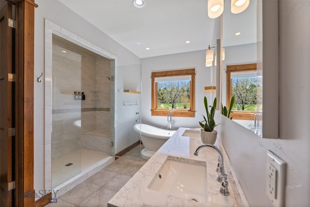 bathroom featuring double vanity, a freestanding tub, a shower stall, a sink, and recessed lighting