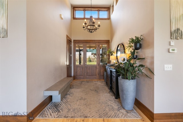 foyer with an inviting chandelier, baseboards, and a towering ceiling