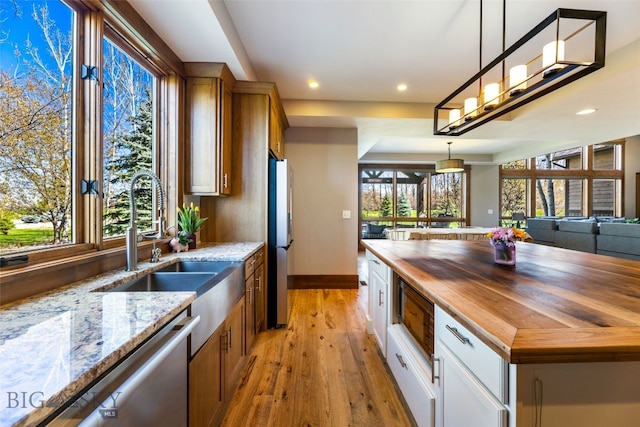 kitchen with butcher block countertops, stainless steel appliances, baseboards, recessed lighting, and light wood-type flooring