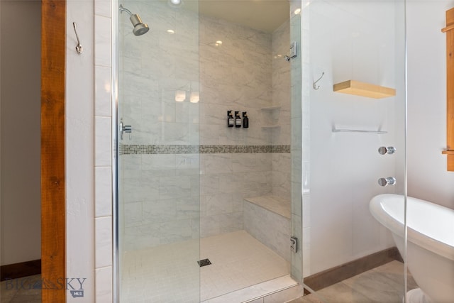 bathroom with baseboards, a soaking tub, and a shower stall