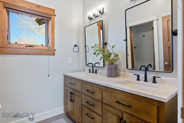 bathroom with a sink, baseboards, and double vanity