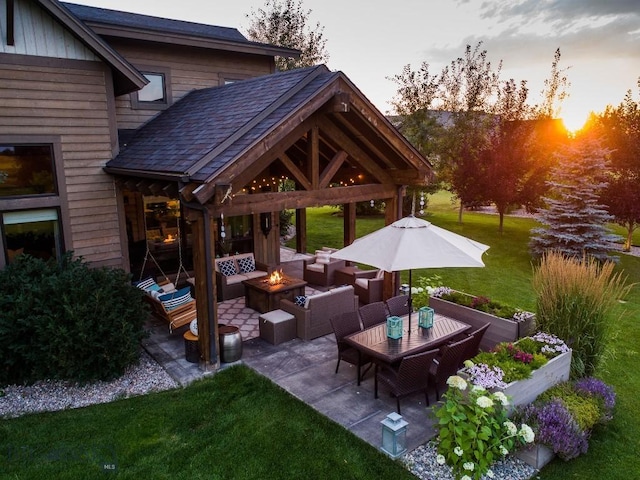 patio terrace at dusk featuring an outdoor living space with a fire pit and a yard