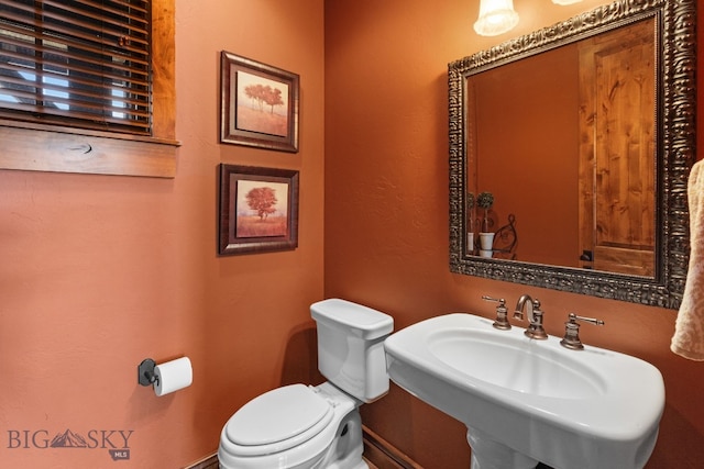 bathroom with a sink, baseboards, and toilet