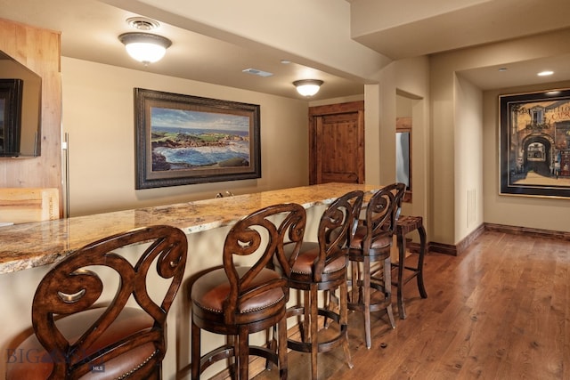 bar with baseboards, wet bar, wood finished floors, and visible vents