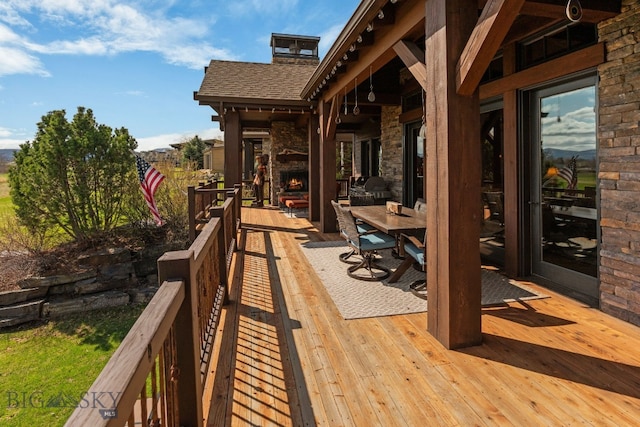 wooden deck featuring an outdoor stone fireplace and outdoor dining area