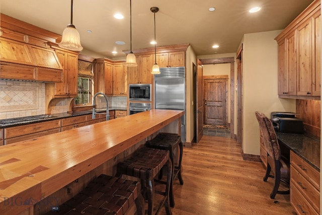 kitchen featuring built in appliances, recessed lighting, decorative backsplash, wood finished floors, and butcher block counters
