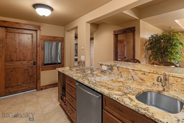 kitchen featuring a sink, light tile patterned floors, light stone countertops, and dishwasher
