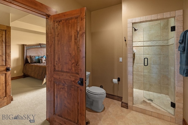 full bathroom with a stall shower, tile patterned floors, baseboards, toilet, and ensuite bathroom