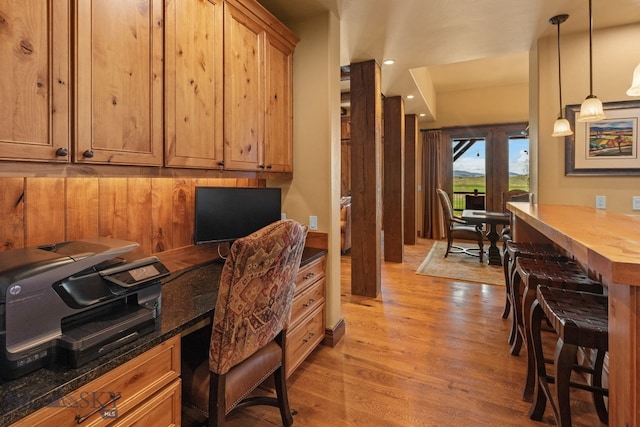 home office with built in study area, recessed lighting, and light wood-style floors