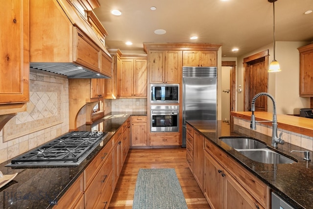 kitchen with a sink, built in appliances, recessed lighting, and light wood finished floors