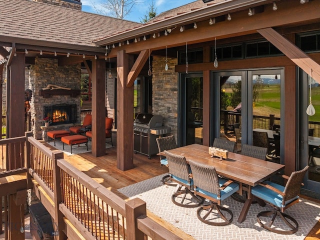 wooden deck featuring outdoor dining area, grilling area, and an outdoor stone fireplace
