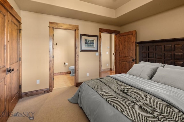 bedroom with light colored carpet, connected bathroom, and baseboards