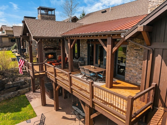 wooden terrace featuring outdoor dining space, a patio, a grill, and an outdoor stone fireplace