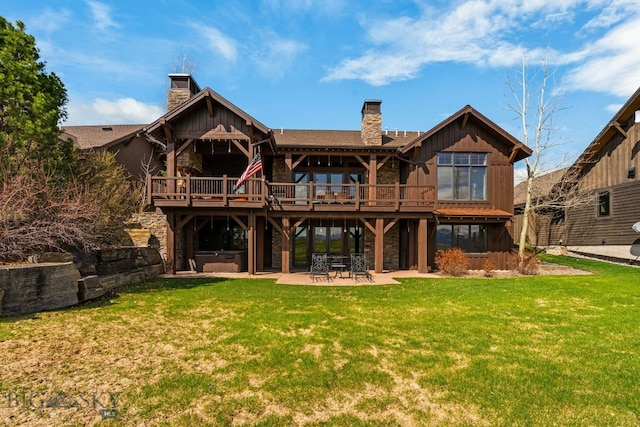 rear view of house with a lawn, a chimney, a hot tub, and a patio area