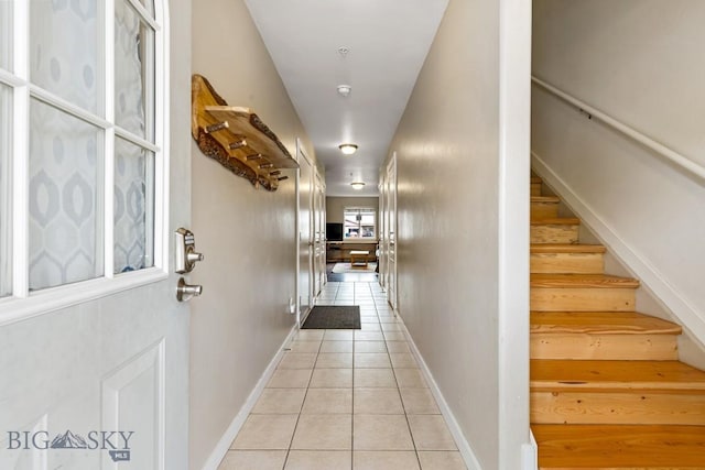 hall with stairs, baseboards, and light tile patterned floors