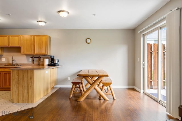 kitchen with baseboards, a sink, light wood-style flooring, and a peninsula