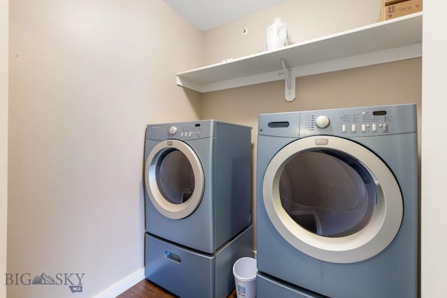 clothes washing area featuring laundry area, washer and clothes dryer, baseboards, and dark wood-type flooring