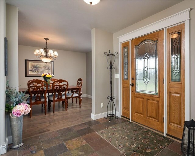 foyer entrance featuring stone finish flooring, baseboards, and an inviting chandelier