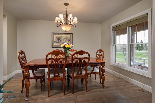 dining space featuring baseboards, an inviting chandelier, and wood finished floors