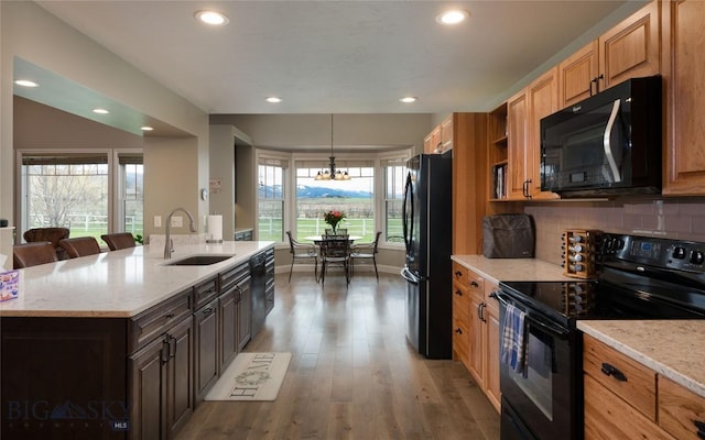 kitchen featuring a sink, light stone countertops, black appliances, and a chandelier